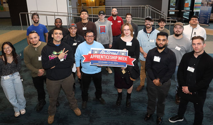 A group of apprenticeships stand together holding a project hire-ed sign