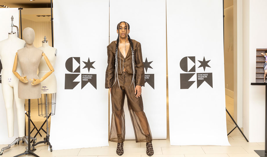 a male student modeling in front of a Chicago Fashion Week draped sign