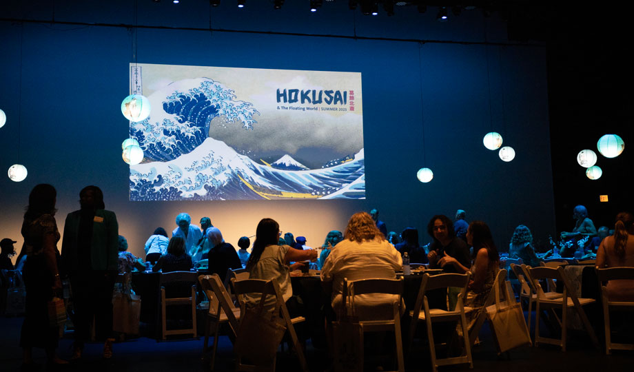 Community members sit and listen to a presentation announcing the Hokusai exhibit