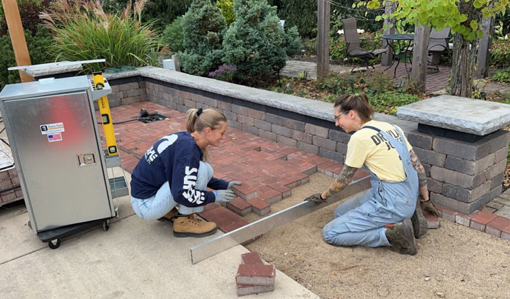 two horticulture students lay pavers down outside