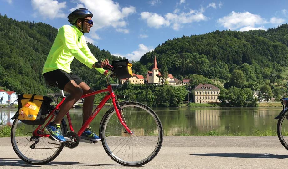 Man on bike riding next to river.