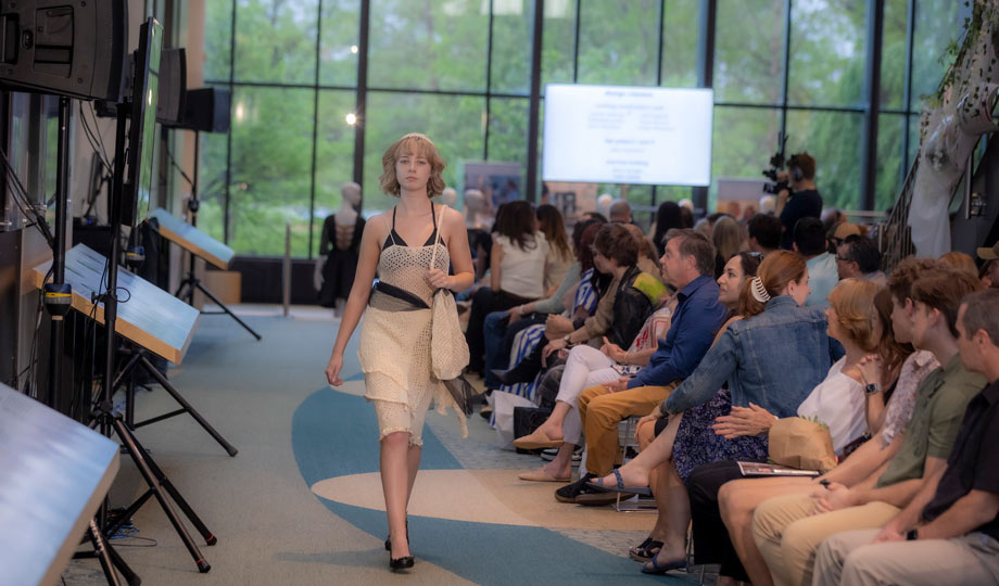 Model walking along runway at fashion show.