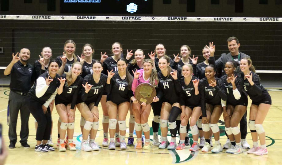 Volleyball team with trophy on court.