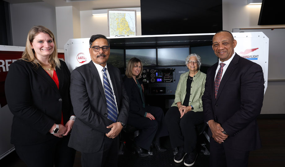 five COD administrators stand in front of an airplane simulator