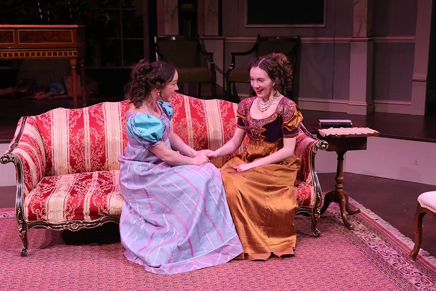 Two actors in dresses sitting on a couch