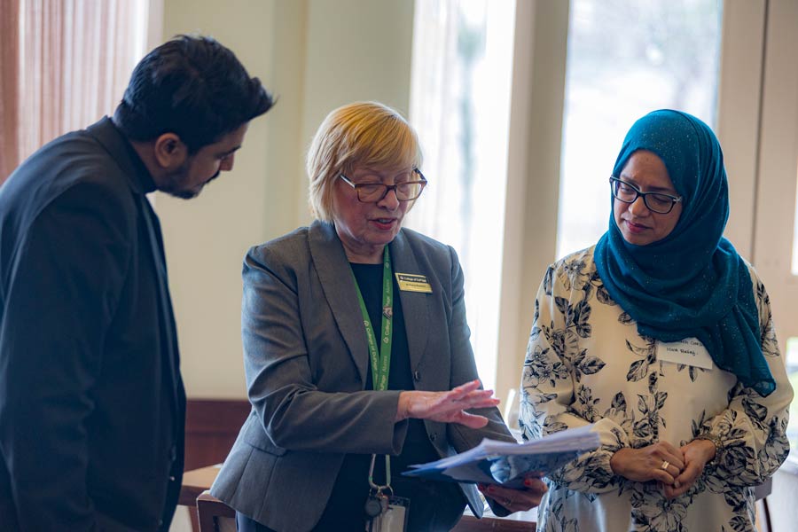 Three people talking about a document with papers in it.