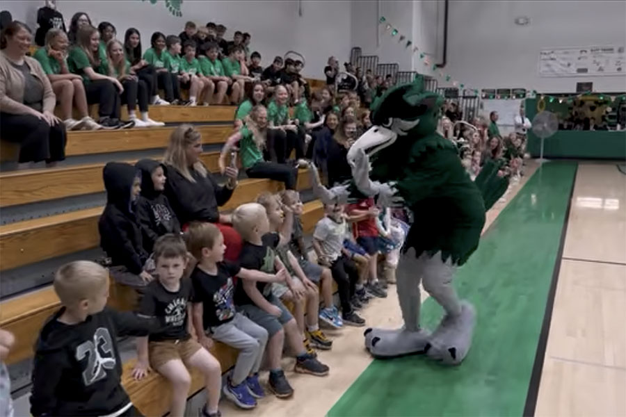 Chappy mascot high-fiving young students in school gym