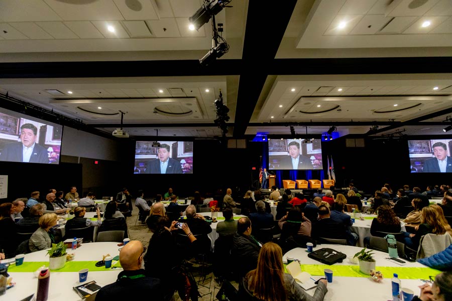 Event attendees watching speaker on screen.