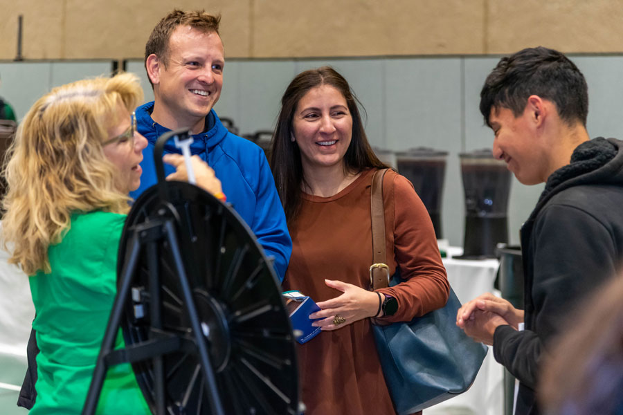 Open house attendees spinning a prize wheel in the Physical Education Center.