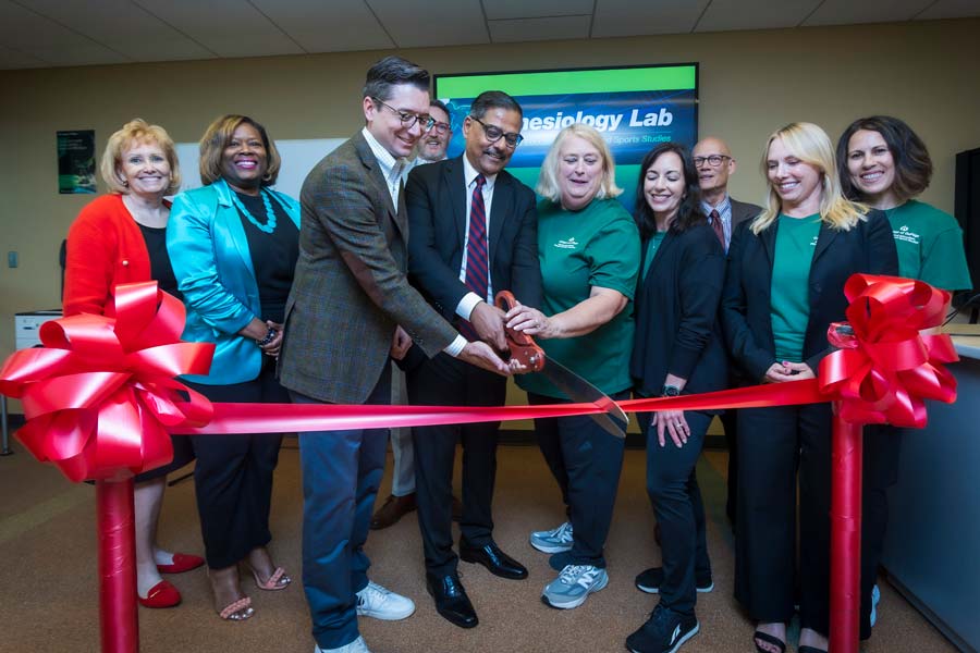 Ten COD leaders cut a large red ribbon in the kinesiology lab