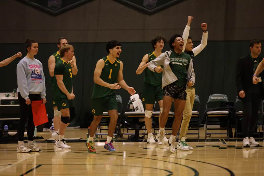 Volleyball team cheering on sideline.