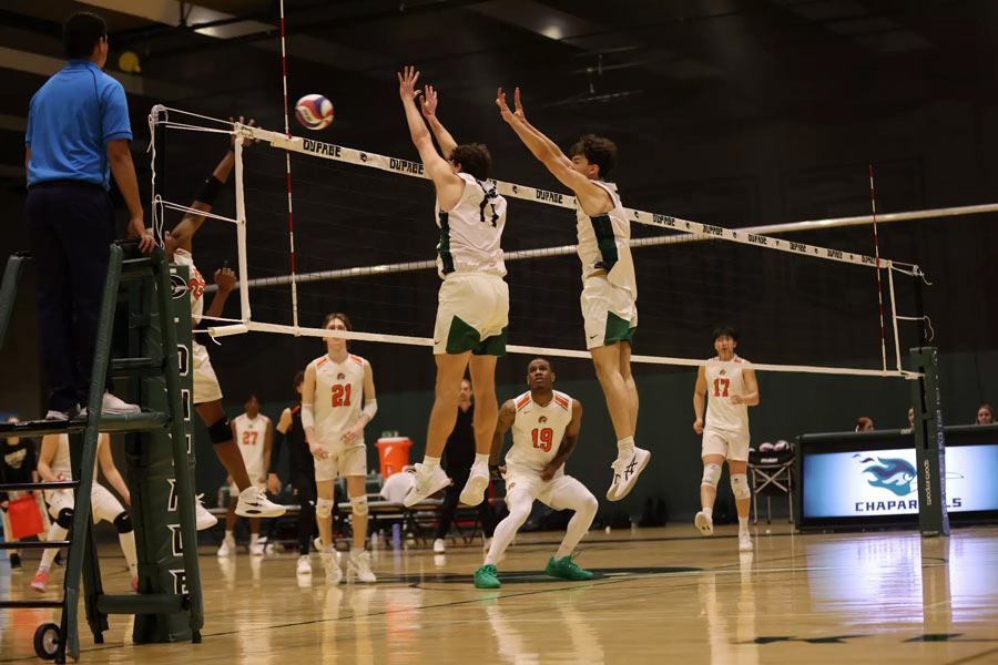 Volleyball players jumping to defend against spiked ball.