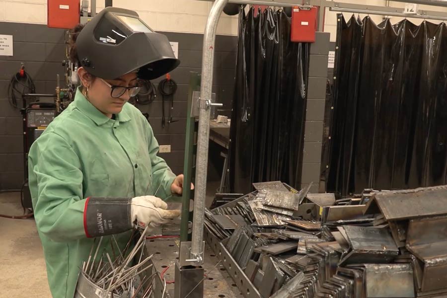 a COD student welds in the welding lab with a face shield