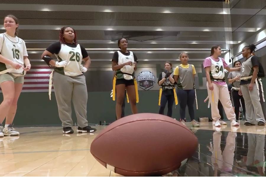 student athletes standing on an indoor court waiting to start a football play